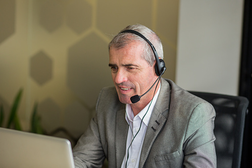 Portrait of businessman hacing a web conference on laptop at office