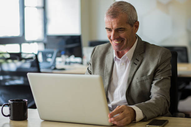 istock Smiling businessman working on laptop during daytime 1867986184