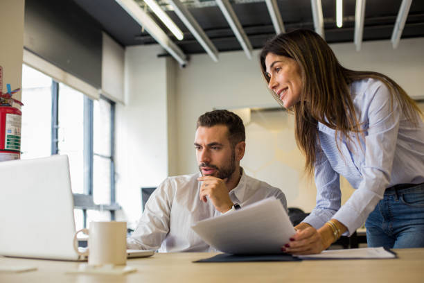 istock Business manager supervising employee works while looking at laptop 1867986232