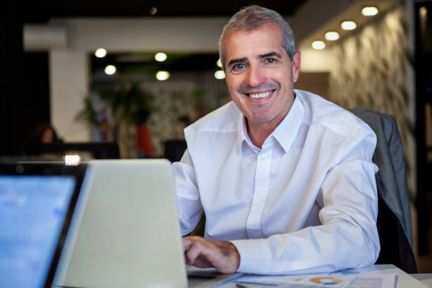 istock Cheerful senior office worker looking at the camera using laptop 1867986276