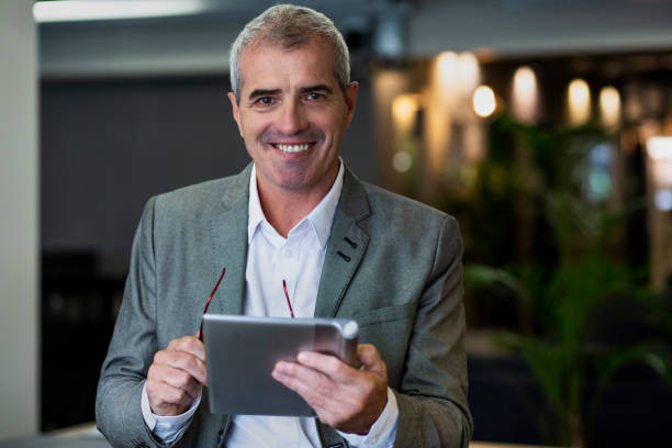 istock Senior businessman looking at the camera while holding digital tablet 1867987303