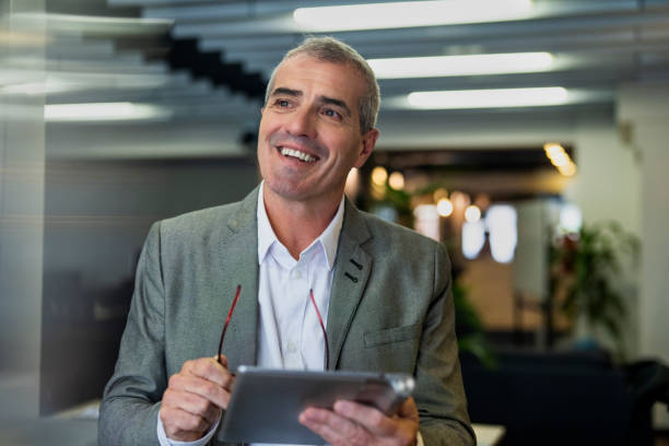 istock Thoughtful senior businessman walking on hallway while holding digital tablet 1867987332