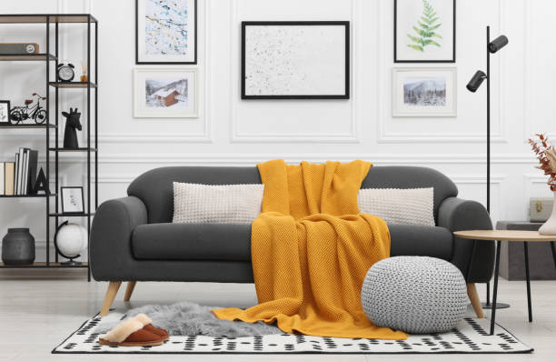 istock Stylish living room interior with comfortable sofa, blanket, side table and ottoman 1867988921