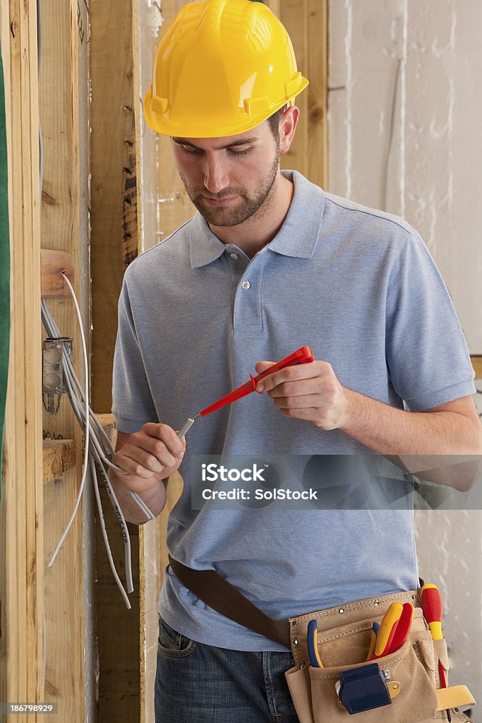 Electrician Working A young male electrician  working on an electrical socket and testing the wire 20-29 Years Stock Photo