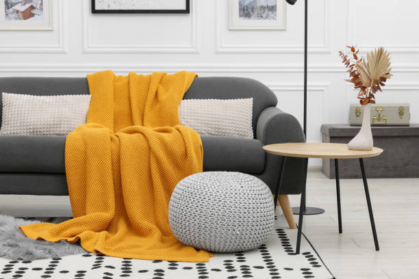 istock Stylish living room interior with comfortable sofa, blanket, side table and ottoman 1867989447