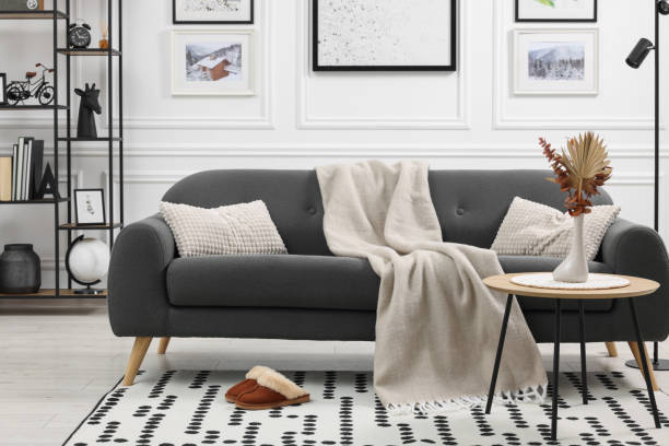 istock Stylish living room interior with comfortable sofa, blanket, slippers and side table 1867989976