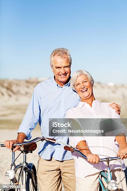 Aktywne Starsza Para Z Rowerów Stojących Na Plaży - zdjęcia stockowe i więcej obrazów 60-64 lata - 60-64 lata, 60-69 lat, Aktywni seniorzy