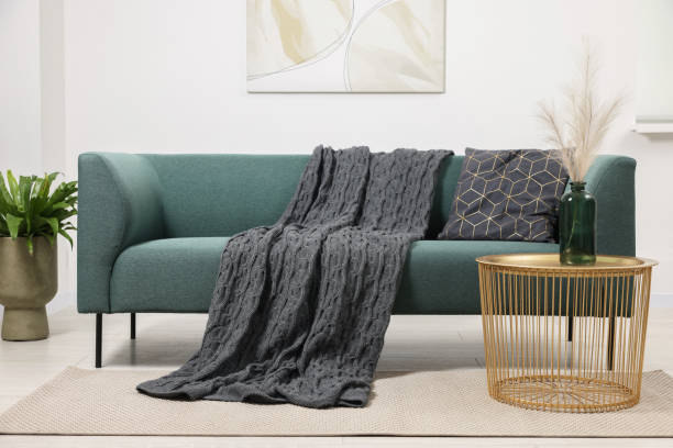 istock Stylish living room interior with comfortable sofa, blanket, houseplant and side table 1867992058