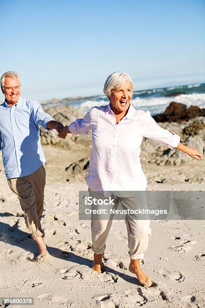 Senior Frau Ziehen Manns Hand Und Fuß Am Strand Stockfoto und mehr Bilder von 60-64 Jahre - 60-64 Jahre, 60-69 Jahre, Aktiver Lebensstil