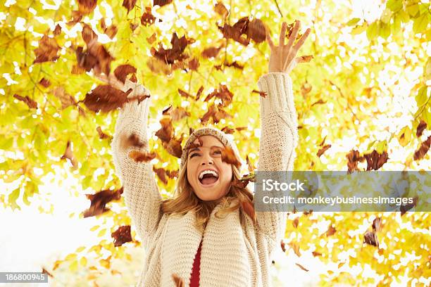 Mujer Tirando Hojas Otoñales En El Aire Foto de stock y más banco de imágenes de Hoja - Hoja, Otoño, Lanzar - Actividad física