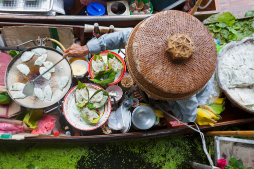 Food vendor at the Damnoen Saduak Floating Market cooking a Thai dessert, Thailand. Slight motion blur.