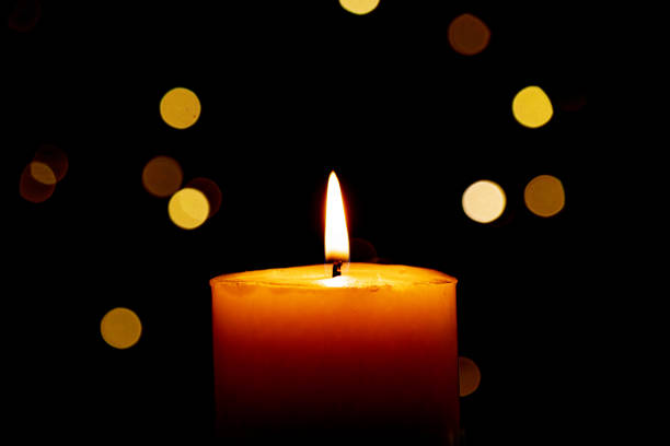 istock Candle burns Isolated On Black background with Christmas Lights Defocused Bokeh. 1868017967