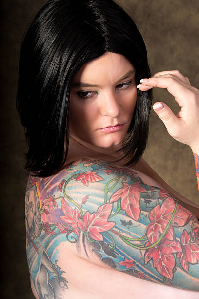 istock Side view of young tattooed woman looking down. 186802913