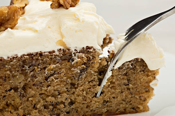 An extreme close up shot of a fork reaching for a bite of banana cake.