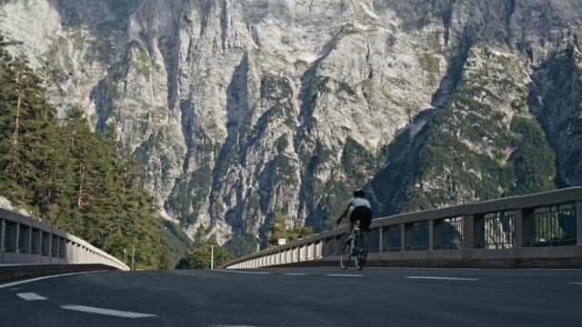 Female Cyclist Riding on Remote Mountain Road Bridge