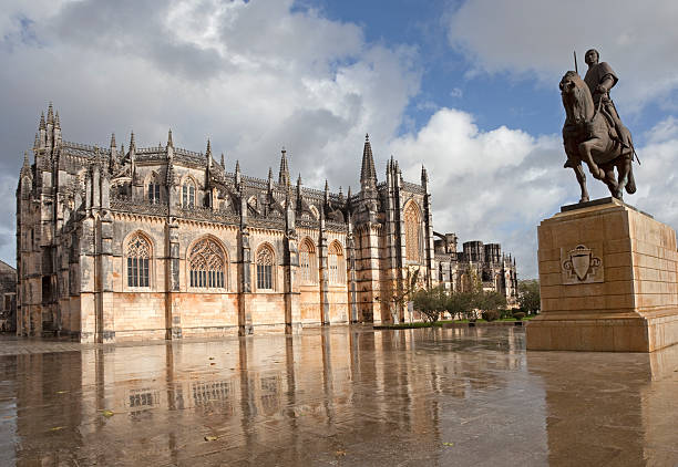 A mother plays with her two children in front of the Mosteiro Santa Maria da Vitória monastery, better known as the Batalha Monastery, and the statue of the famous Portuguese saint Nuno Alvares Pereira in Batalha, Beira Litoral, Portugal.