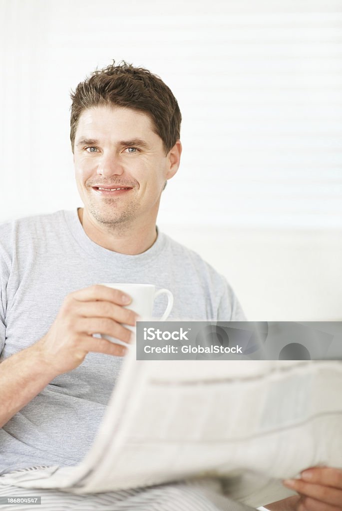 Smiling man holding a coffee cup and newspaper Portrait of a handsome mid adult man drinking a cup of coffee while reading the newspaper 30-39 Years Stock Photo