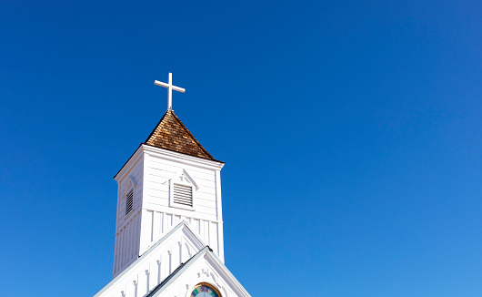 Wooden Church Steeple with Cross. White Old Church, Blue Sky On Background. Copy Space For Text. Christian Religious Holiday Easter or Radonitsa. Horizontal Plane