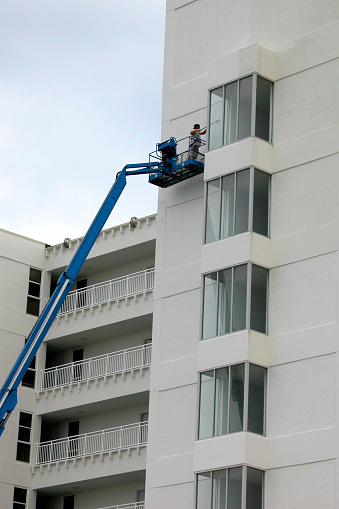 Person on lift painting a condominium hotel white