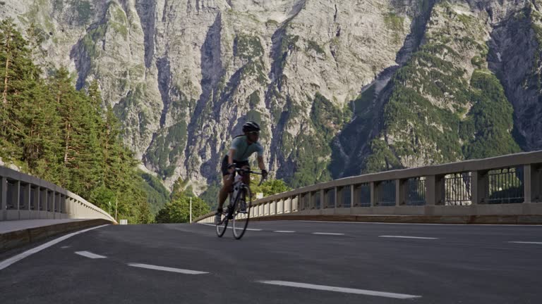 Woman cycling on sunny mountain road bridge