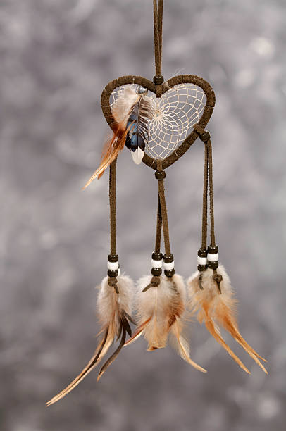 Heart Shaped Dreamcatcher "According to legend,  the first dreamcatcher was created by a spider and was made of horsehair, feathers, beads and her web. When hung above the bed, good dreams will pass through the center and bad dreams are trapped in the web where they perish in the light of dawn." symbol north american tribal culture bead feather stock pictures, royalty-free photos & images