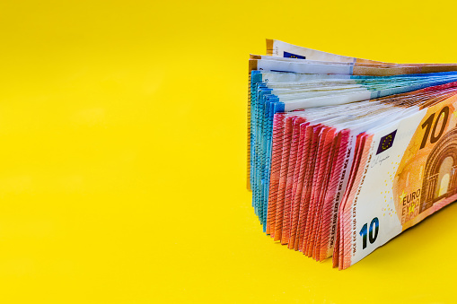 Madrid, Spain. A stack of euro bills on a yellow background with copy space.