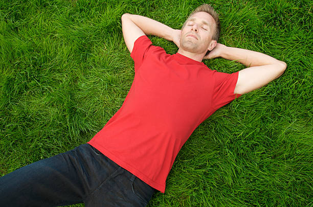 istock Guy in Red T-Shirt Lies on Thick Green Grass 186806217