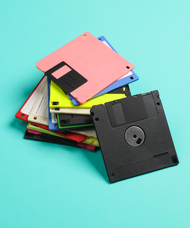 Black and colored floppy disks on blue background. Computer technology 80s.