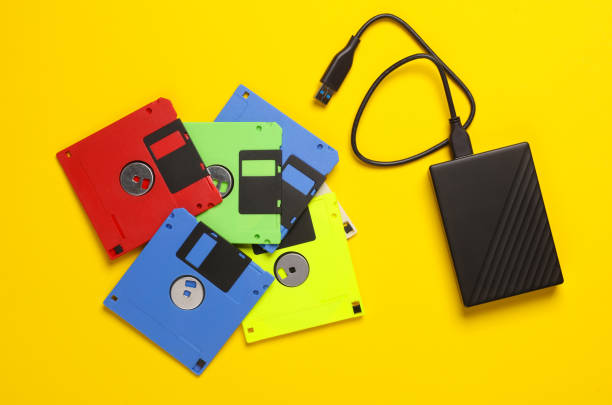 istock New and old technologies. Retro floppy disk and modern external hard drive on a yellow background. Top view 1868070486