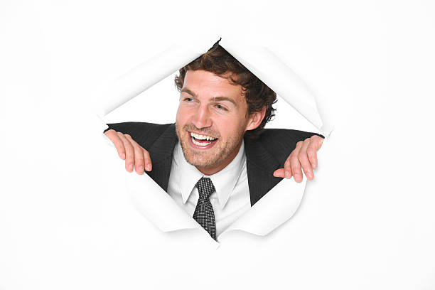 Happy businessman peering through torn paper