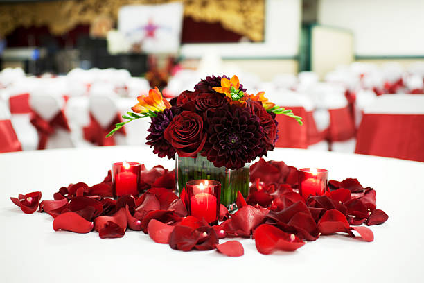 Focus on full view of a table center piece at a wedding reception: vase with flowers surrounded by lit candles and rose petals. Copy space. CLICK FOR SIMILAR IMAGES AND LIGHTBOX WITH MORE WEDDING IMAGES.