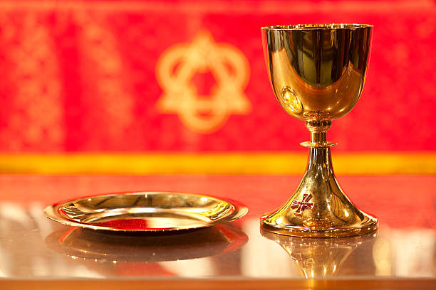 Gold chalice and tray against red and gold background with Trinity symbol; Christmas in the church