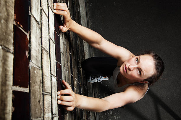Young woman doing a Wall Run a Parkour move that is done to ascend a wall or tall object by using one or more steps to propel your body upward. Horizontal shot