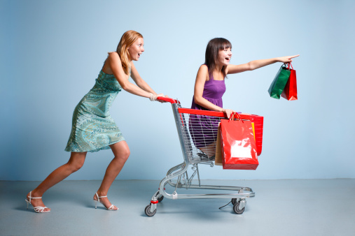 A  woman wheeling a younger woman  in a shopping cart