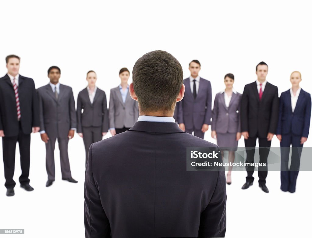 Businessman Applauded by Colleagues Rear view of a businessman standing before his co-workers as the applaud him. Horizontal shot. Adult Stock Photo