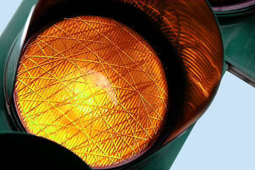 Close-up on an amber traffic light. Other traffic lights in: