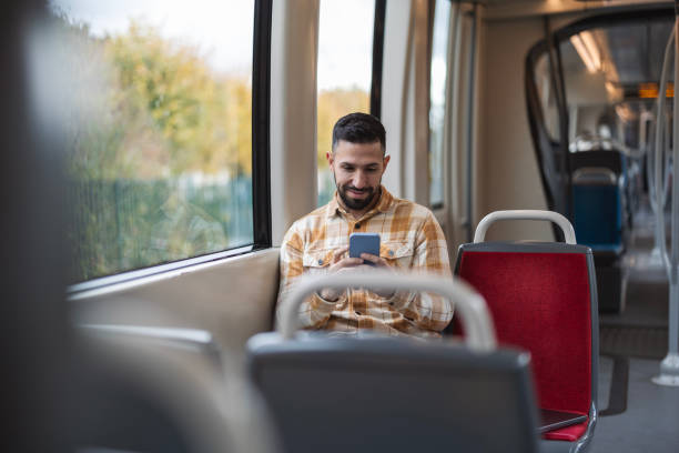 istock attractive Hispanic man sitting on the train heading to his date while chatting on his smartphone 1868110566