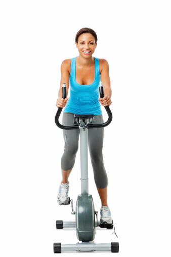 Studio shot of cheerful young female exercising on exercise bike. Vertical shot. Isolated on white.