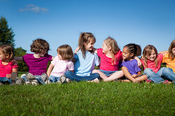 8 つの幸せな女の子のシッティングエリアと沿うもの - children only child huddle sun ストックフォトと画像