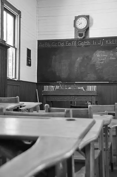 The view from a student's desk towards the blackboard in a rural 1903 classroom. Black and White