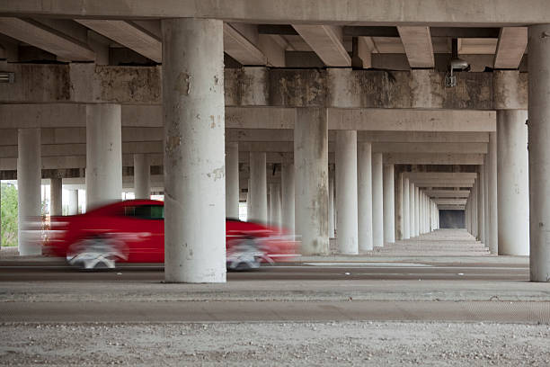 Concrete columns of elevated freeway with blurred red car stock photo