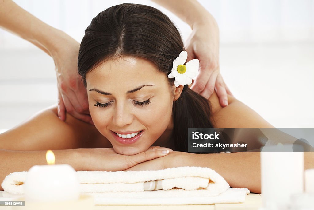 Beautiful brunette receiving a back massage. Young smiling woman with closed eyes is enjoying in the massage. White background. Adult Stock Photo