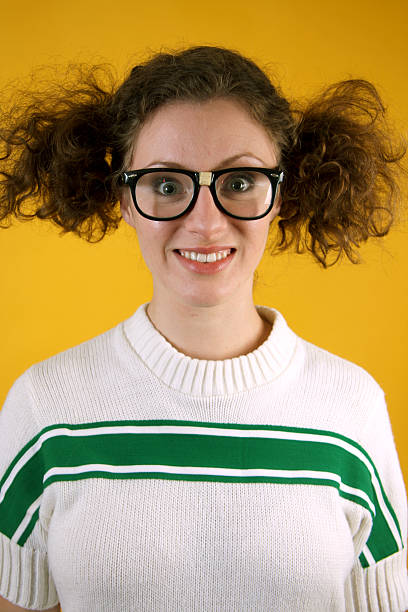 Nerdy Teenage Girl/Woman Nerdy looking teenage girl/young woman wearing a sweater and a pair of taped glasses on a yellow background. In the style of a high school portrait.  Related Images with this Model: high school photos stock pictures, royalty-free photos & images