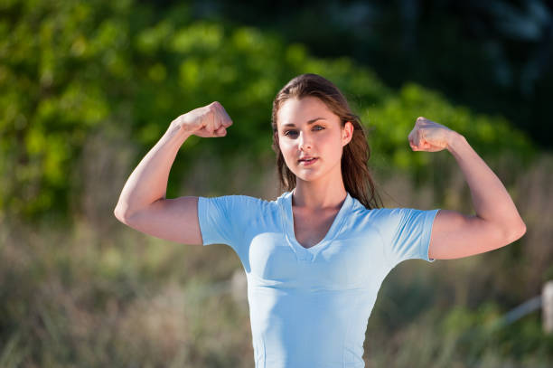 istock Young Brunette Fitness Model Flexing Muscles on Beach 186813398