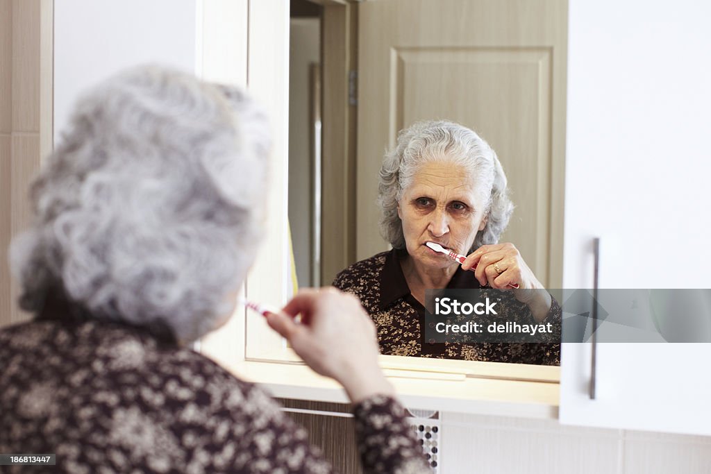 Dental Hygiene Senior woman brushing her teeth with reflection in mirror Active Seniors Stock Photo