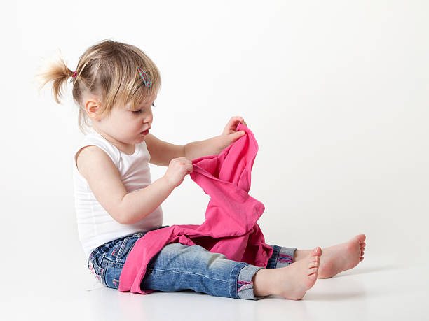 istock toddler trying to put on her sweater 186814057