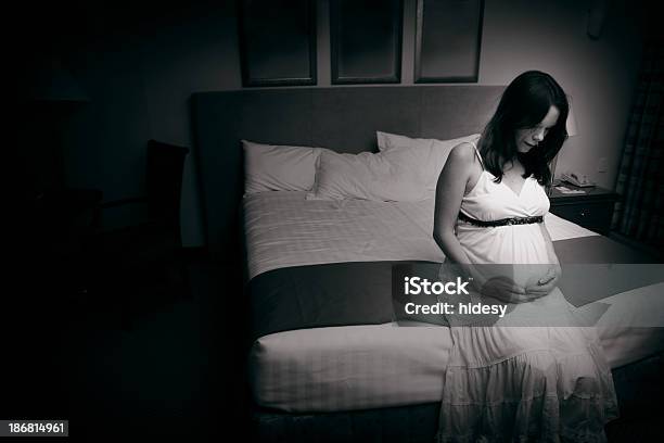 A Black And White Photo Of A Pregnant Woman Sat On The Bed Stock Photo - Download Image Now