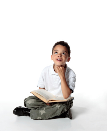 Little boy of mixed race reading book and imagining future
