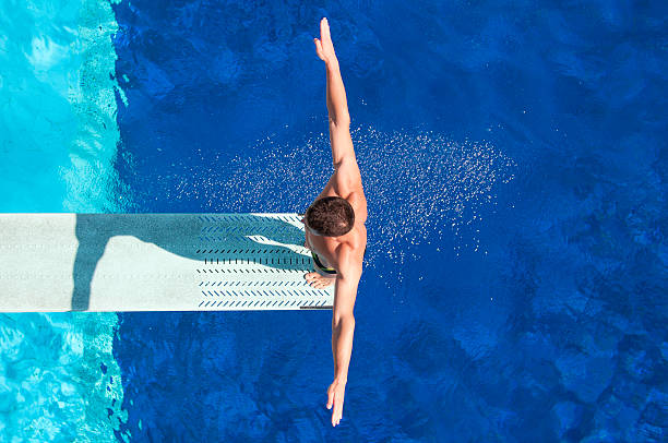 Springboard diving competitor "Springboard diving competitor concentrating before the dive. Shot from above, polarizing filter" diving board stock pictures, royalty-free photos & images