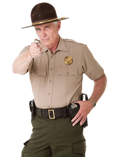 Mature Highway Patrolman Pointing Portrait of a mature male law enforcement officer (highway patrol, sheriff, or park ranger) pointing at the viewer. Isolated on a pure white background. park ranger stock pictures, royalty-free photos & images